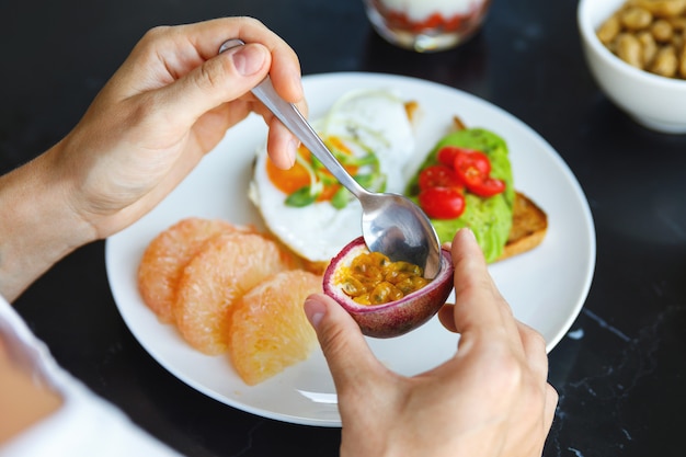 Sana colazione - La donna sta mangiando frutto della passione fresco.