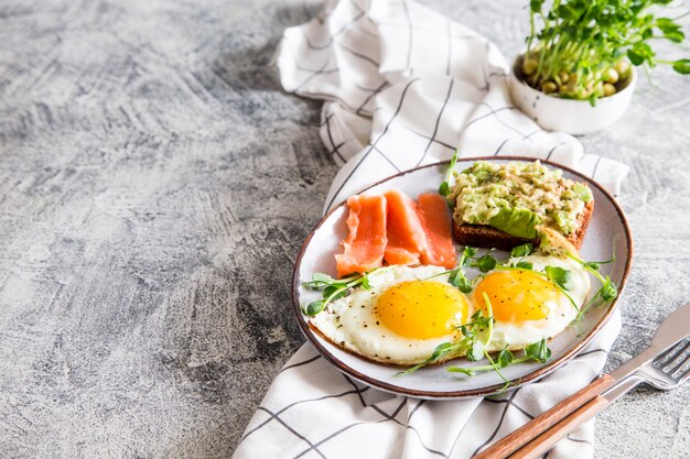 Sana colazione nutriente con uova, salmone, sandwich di avocado e semi di pisello germogliati