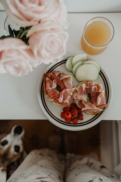 Sana colazione sul tavolino accanto al letto, con fiori e un simpatico cane