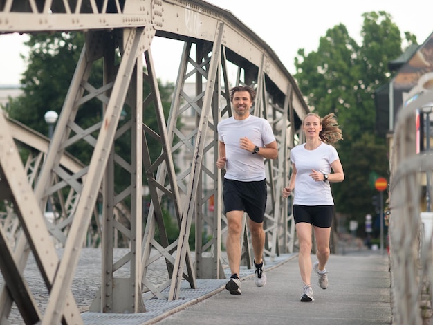 sana coppia matura fare jogging in città al mattino presto con l'alba sullo sfondo