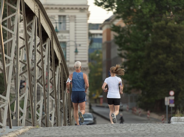 sana coppia matura fare jogging in città al mattino presto con l'alba sullo sfondo