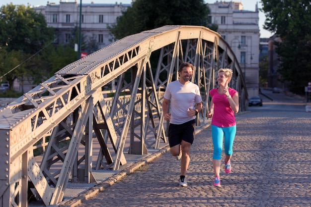 sana coppia matura fare jogging in città al mattino presto con l'alba sullo sfondo