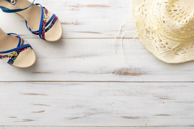 Sandali femminili con concetto di sfondo estivo, cappello di paglia su superficie in legno chiaro