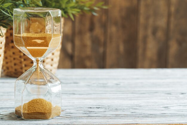 Sandglass sulla fine di legno del bakground in su. Concetto di tempo