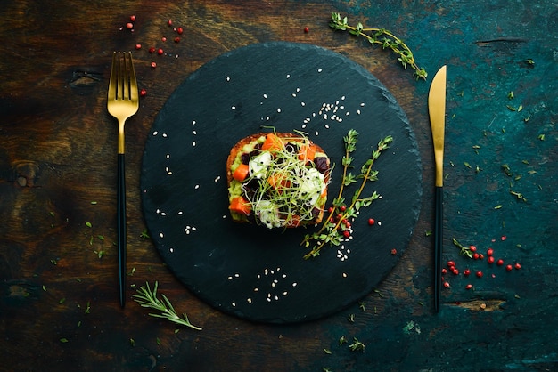 Sandwich ciabatta avocado barbabietole e carote Colazione su una lastra di pietra nera