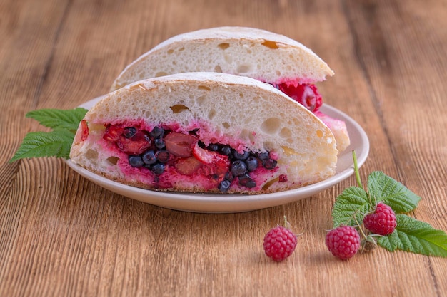 Sandwich di ciabatta con lamponi crudi mirtilli e ciliegie su un piatto da vicino