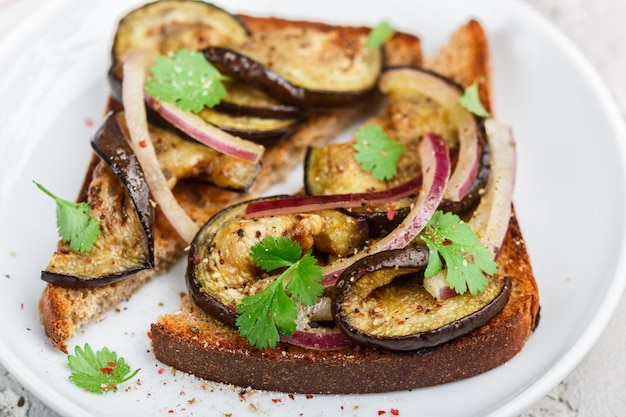 Sandwich di pane di segale con melanzane fritte o al forno, cipolla rossa, coriandolo e spezie. Antipasto Mediterraneo.