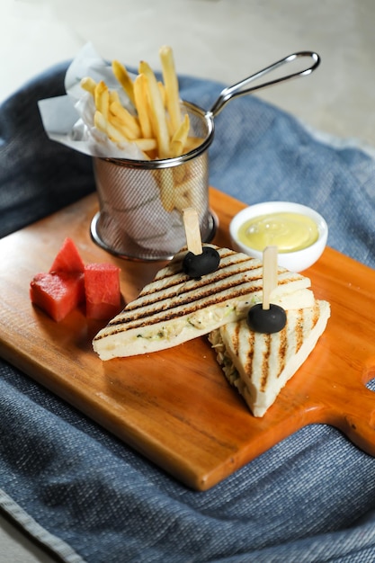 Sandwich di pollo alla griglia con secchio di patatine fritte servito in tavola di legno isolato sul tovagliolo vista laterale del cibo per la colazione