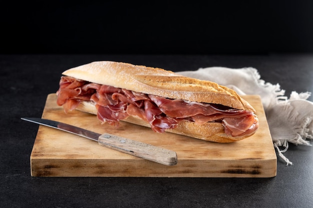 Sandwich di prosciutto serrano spagnolo su sfondo nero ardesia