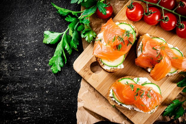 Sandwich di salmone su un tagliere con erbe aromatiche e pomodori