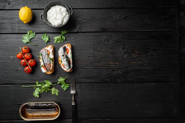 Sandwich di sardine con pesce affumicato su tavolo in legno nero sfondo vista dall'alto piatto con copia spazio per il testo