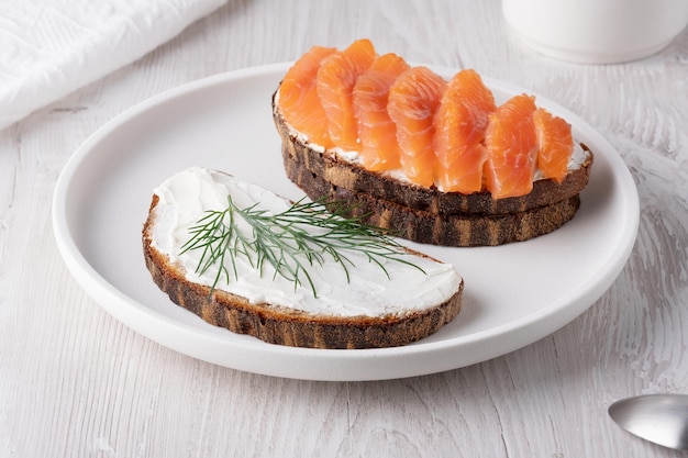 Sandwich di segale con salmone e formaggio a crema su un tavolo bianco di legno