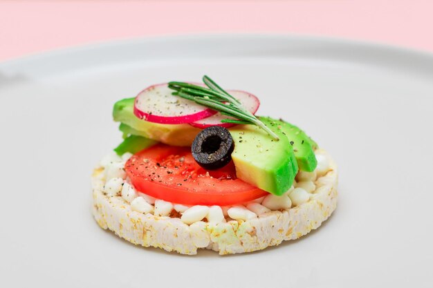 Sandwich di torta di riso con ricotta di avocado, pomodoro, olive e ravanello