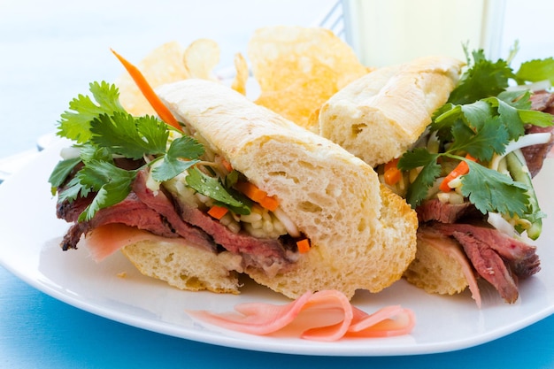 Sandwich gourmet banh-mi con patatine sul lato.