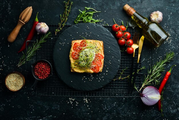 Sandwich Pezzo fresco di ciabatta con pomodori hummus e uova Colazione su una lastra di pietra nera