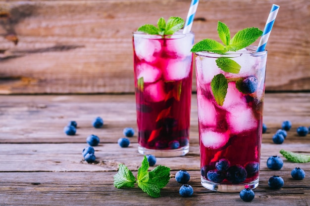 Sangria di ghiaccio al mirtillo con menta in bicchieri su fondo di legno