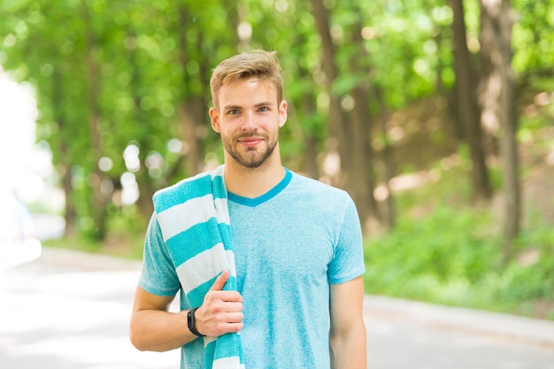 Sano e attivo. Uomo biondo. Uomo bello che indossa una maglietta casual con asciugamano sul paesaggio naturale. Uomo con i capelli non rasati e un taglio di capelli alla moda. Uomo caucasico il giorno d'estate.