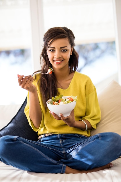 Sano e yum Ritratto di una giovane donna che mangia un'insalata a casa