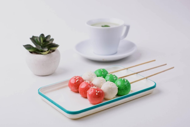 Sanshoku Dango tre gnocchi colorati con tè matcha isolati su sfondo bianco