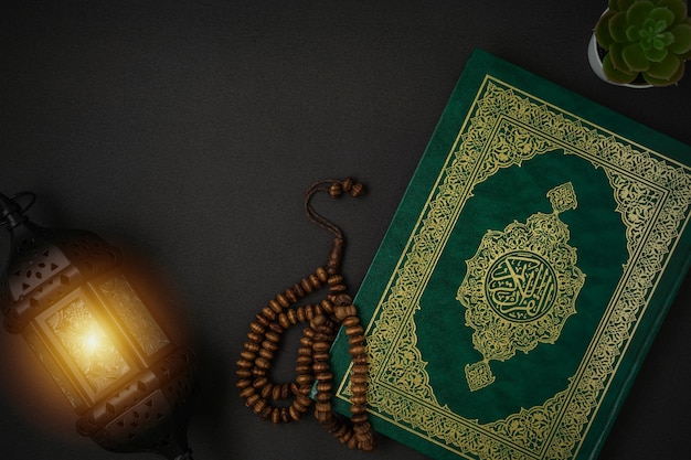 Santo Al Quran con scritto calligrafia araba significato di Al Quran e rosario su sfondo nero con uno spazio di copia