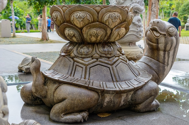 Sanya, Hainan, Cina - 20 febbraio 2020: Tartaruga di pietra modellata con vasca e acqua sul retro sul territorio del centro buddista Nanshan.