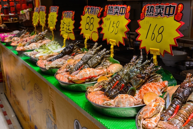 Sanya, Hainan/Cina - 7 gennaio 2020: Cibo di strada cinese. Commercio ambulante. Tipi cinesi di pesce fresco in un mercato asiatico di pesce a Sanya, provincia di Hainan, Cina. Iscrizione: nome cibo.