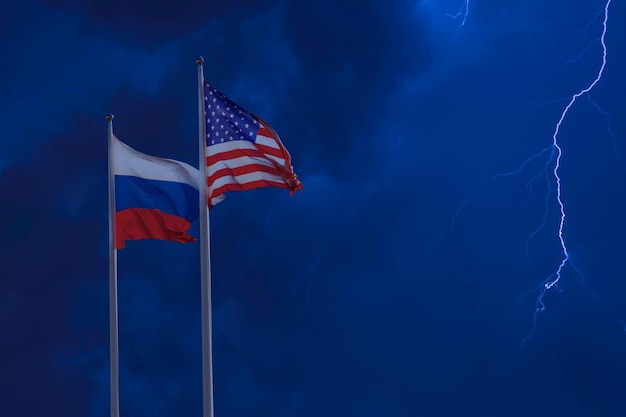 Sanzioni e concetto di confronto. Bandiere della Federazione Russa e degli Stati Uniti d'America sullo sfondo del cielo notturno con fulmini