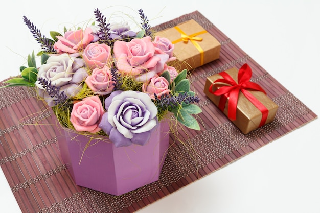 Sapone fatto in casa a forma di rose e scatole regalo sul tovagliolo di bambù