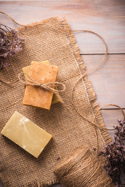 Sapone naturale con fiori secchi su fondo in legno.