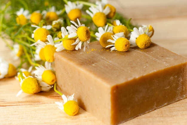 Sapone organico con fiori di camomilla sul tavolo di legno