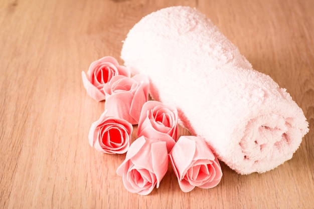 Sapone sotto forma di rose e un asciugamano su un fondo di legno