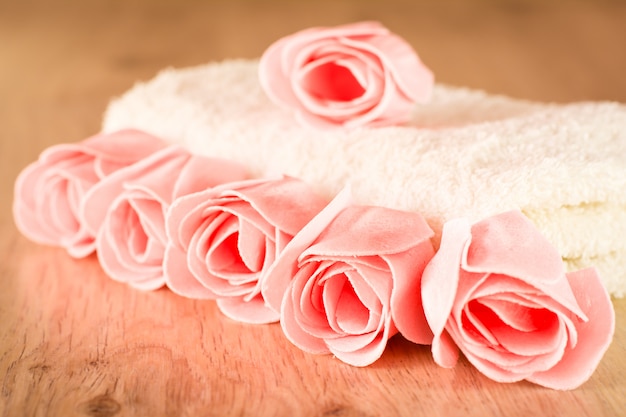 Sapone sotto forma di rose e un asciugamano su un fondo di legno