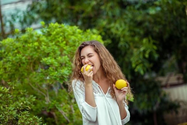 Sapore di agrumi. Donna in bianco che tiene due limoni nelle mani