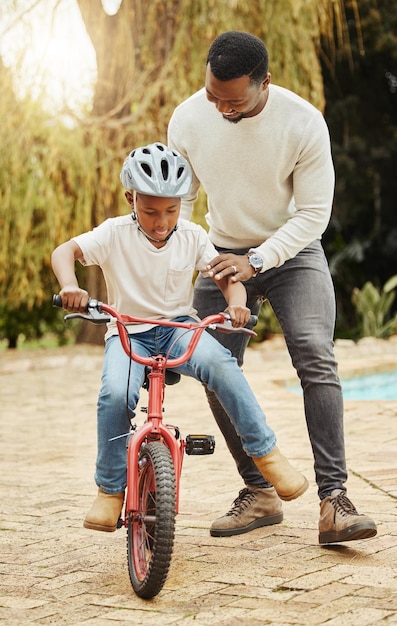 Sapore di libertà. Inquadratura di un adorabile ragazzo che impara ad andare in bicicletta con suo padre all'aperto.