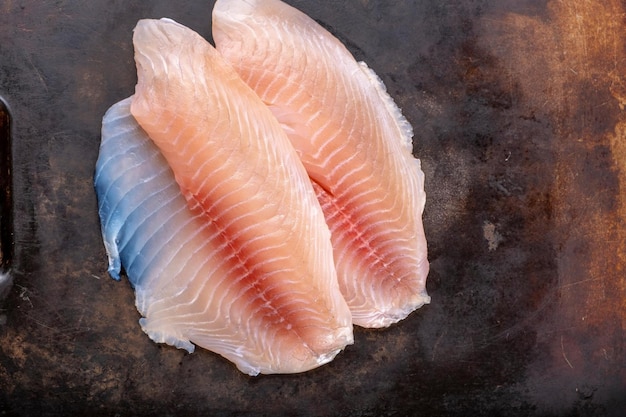 Sapori squisiti Primo piano del filetto di pesce tilapia crudo infuso con deliziose spezie in 4K