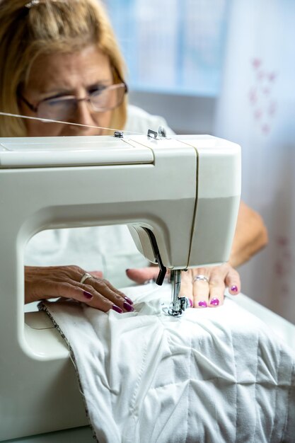 Sarta donna con gli occhiali che si concentra mentre cuce alla macchina da cucire