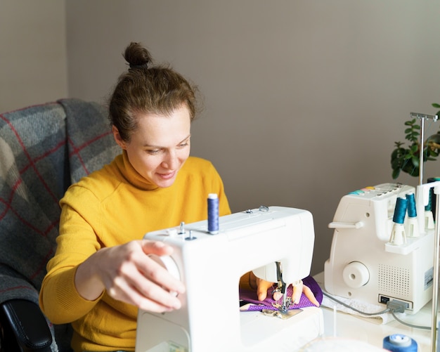 Sarta femminile che utilizza la macchina da cucire mentre lavora a casa