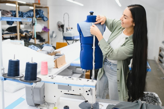 Sarta femminile felice che lavora con la macchina da cucire alla fabbrica tessile