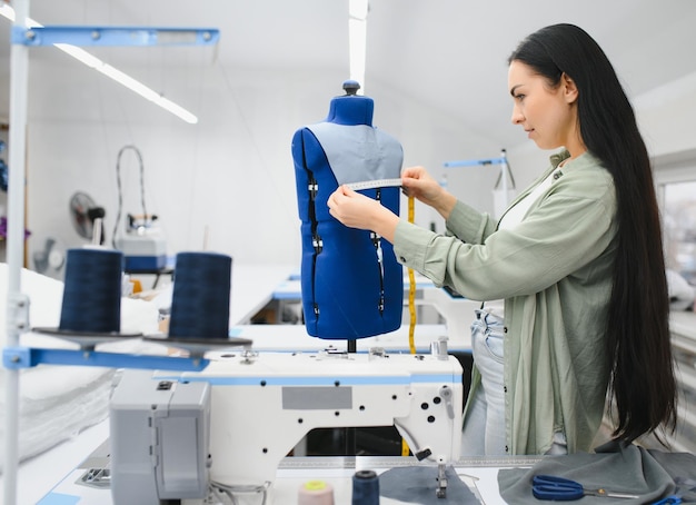 Sarta femminile felice che lavora con la macchina da cucire alla fabbrica tessile