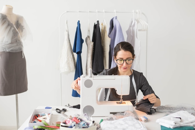 Sarta, moda, sarto e concetto di persone - giovane stilista femminile che lavora nel suo showroom.