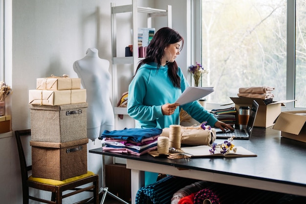 Sarta stilista di moda su misura di giovane donna utilizzando il computer portatile in studio di sarta