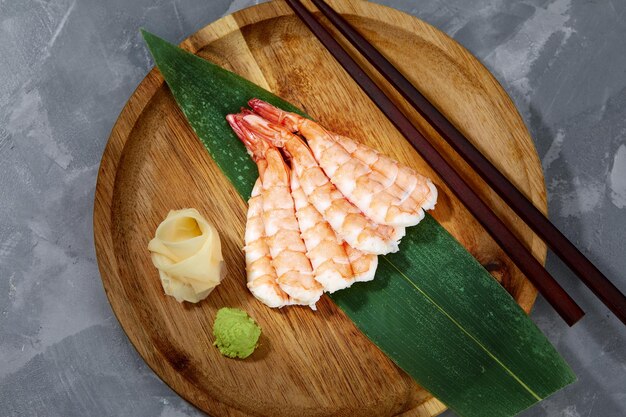 Sashimi con gamberi su foglia di bambù su tavola di legno