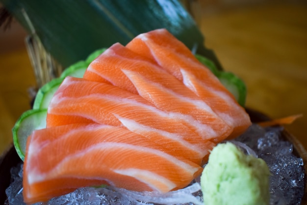 Sashimi crudo di color salmone sul piatto tradizionale giapponese marrone sulla tavola nera. Chiuso.