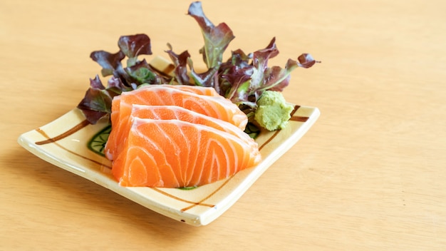 Sashimi di color salmone fresco su una tavola di legno.