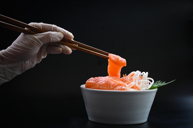 Sashimi di salmone cibo filetto di salmone menu giapponese con le mani tenevano le bacchette per tenere il sashimi di salmone pesce salmone crudo fresco per cucinare cibo frutti di mare pesce