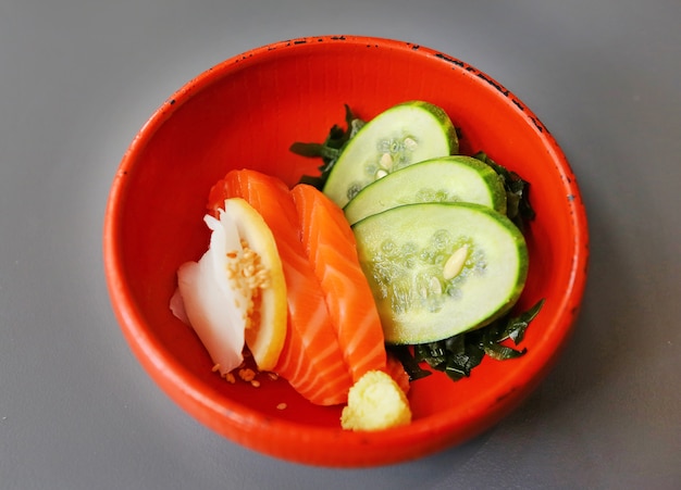 Sashimi di salmone in una piccola ciotola rossa.