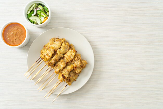 Satay di maiale con sottaceti di salsa di arachidi che sono fette di cetriolo e cipolle in aceto - Stile di cibo asiatico