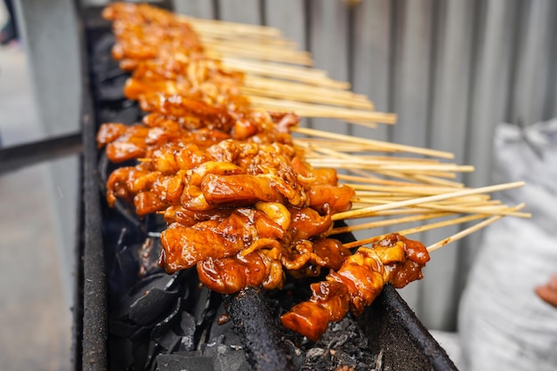 Satay di pollo alla griglia sul tradizionale fuoco di carbone. spiedini di carne bruciano di fumo