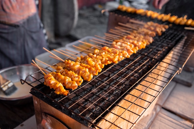 satay di pollo alla griglia sulla piastra delle griglie con fumo. cibo di strada asiatico