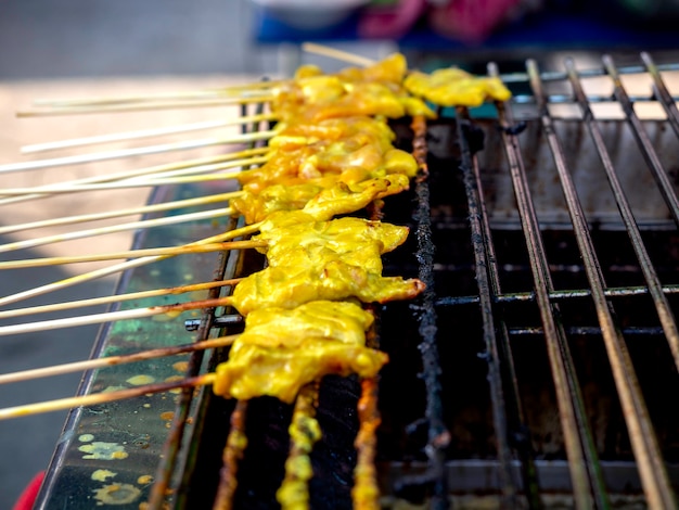 Satays di maiale alla griglia che grigliano sulla stufa. Fila di griglia di arrosto di maiale barbecue o arrosto di maiale satay